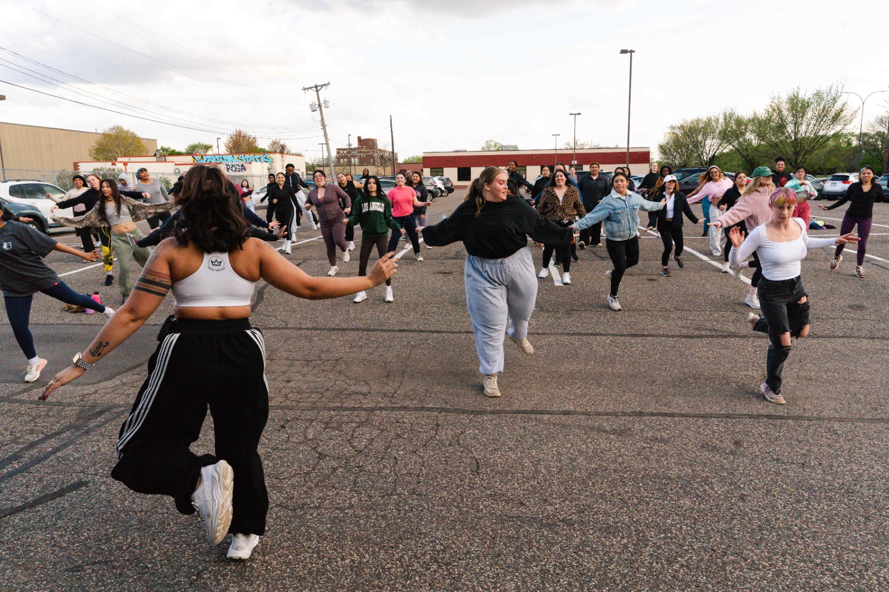 Instructor leading a wide-arms move at an outdoor pop-up class
