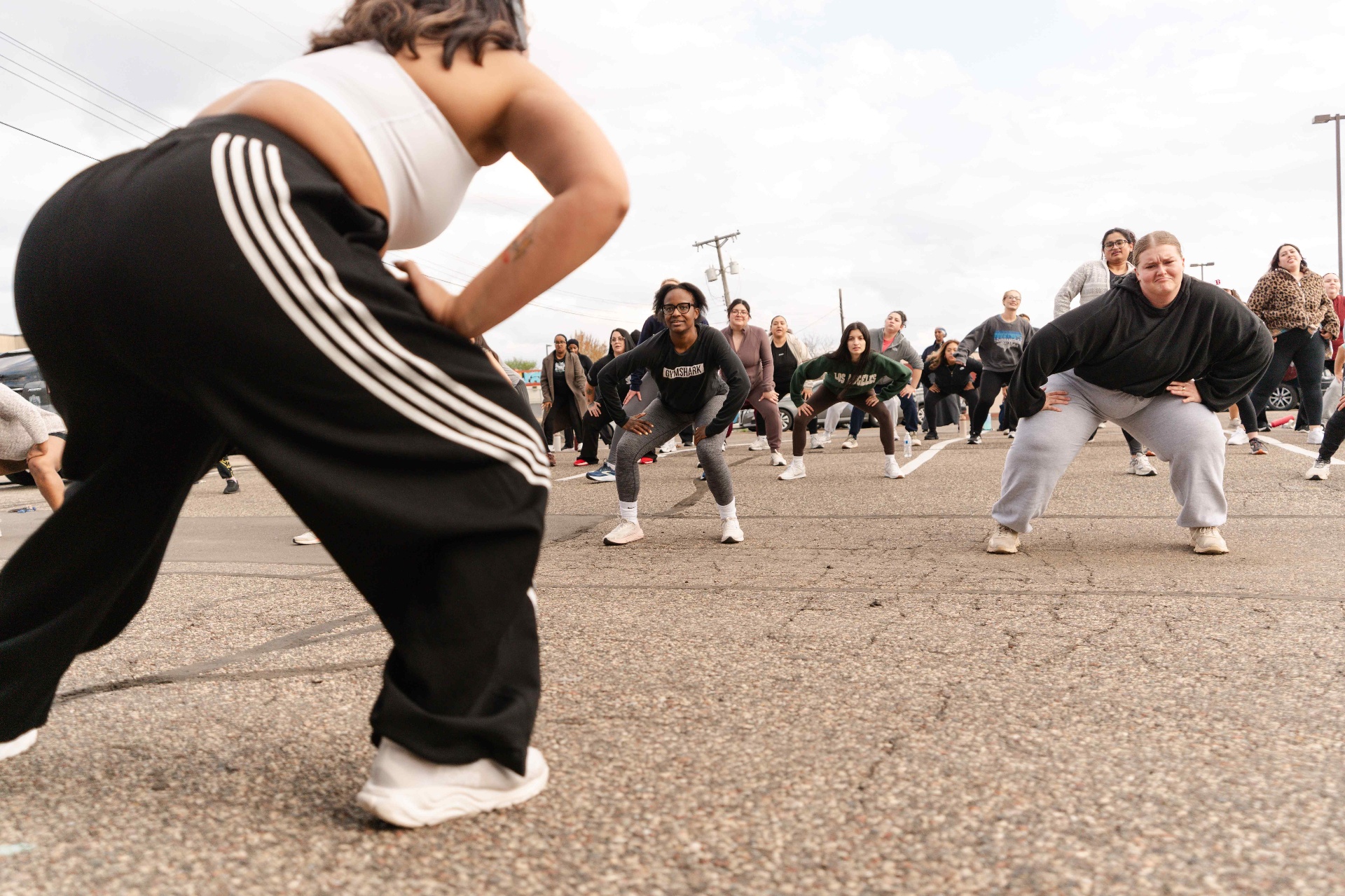 Low-angle shot of dancers squatting in unison at a parking-lot class
