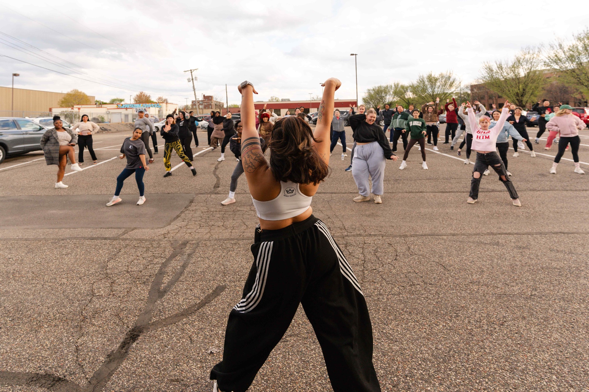 Instructor leading a high-energy outdoor Turn Up Dance Fitness class with arms raised
