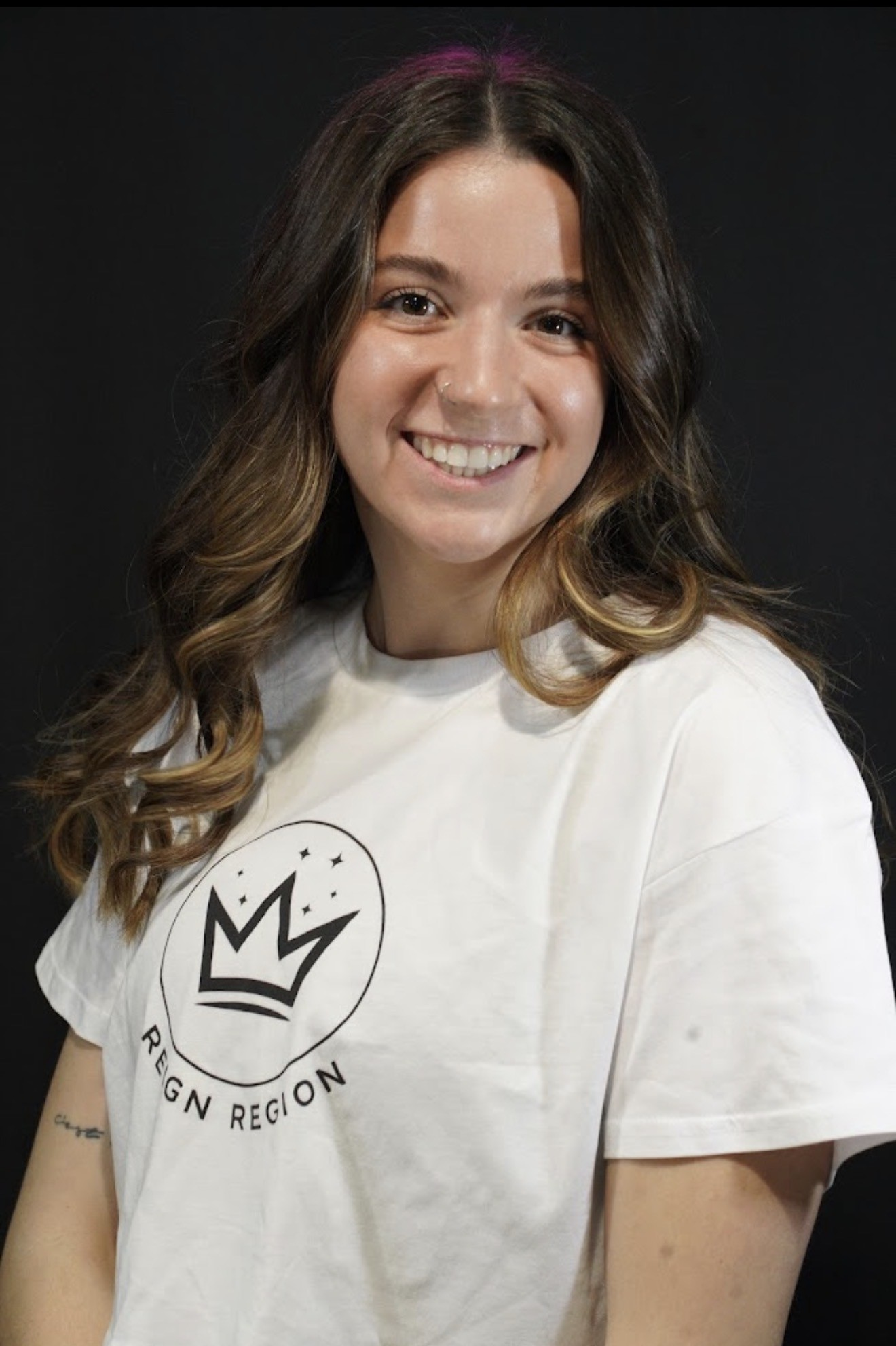 Reign Region team member smiling in a white crown logo tee